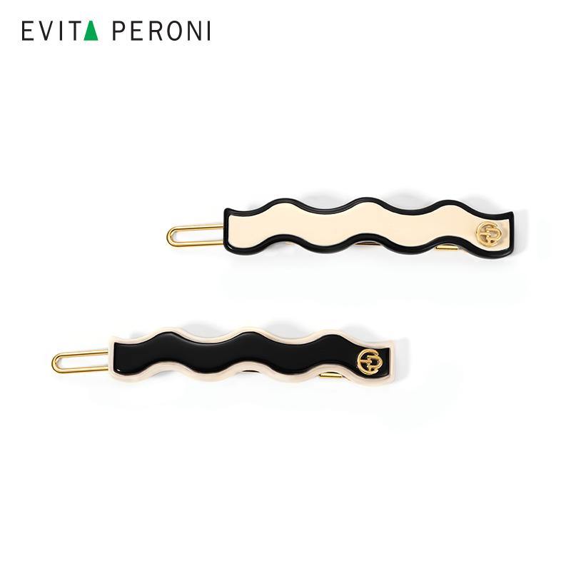 Wavy black and cream enamel hair barrettes with gold-tone accents on white background