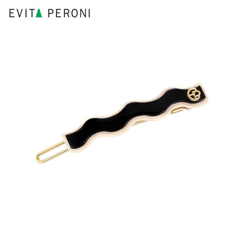 Wavy black enamel hair barrette with gold-tone clip and decorative accent on white background
